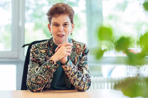 Foto van Aline achter bureau.