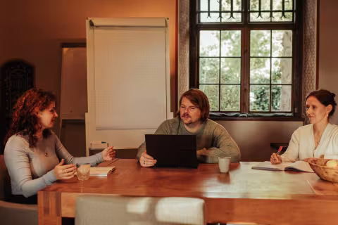 Overleg van drie mensen aan tafel