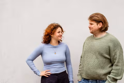 Man en vrouw staan naast elkaar en kijken elkaar vriendelijk aan.