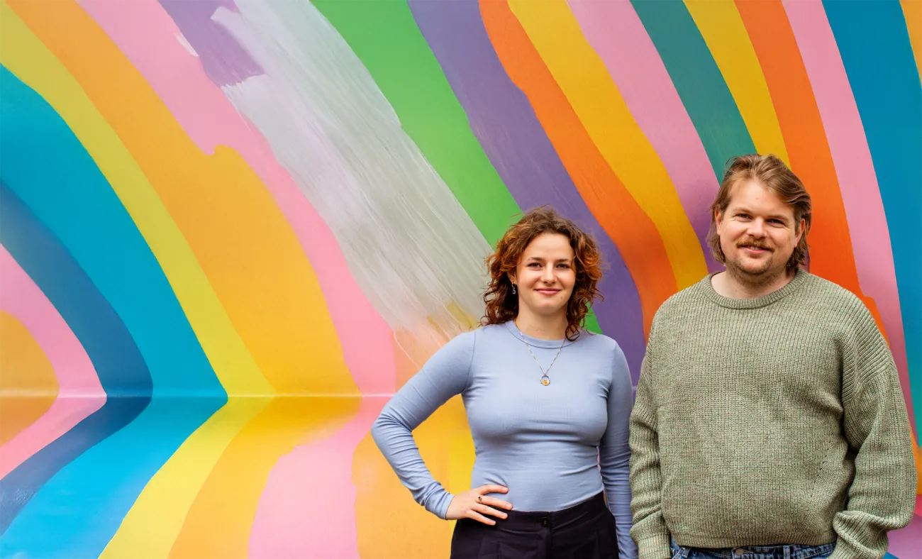 Portret van duo met een kleurige achtergrond.