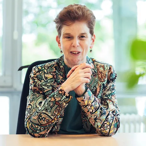 Foto van Aline achter bureau.